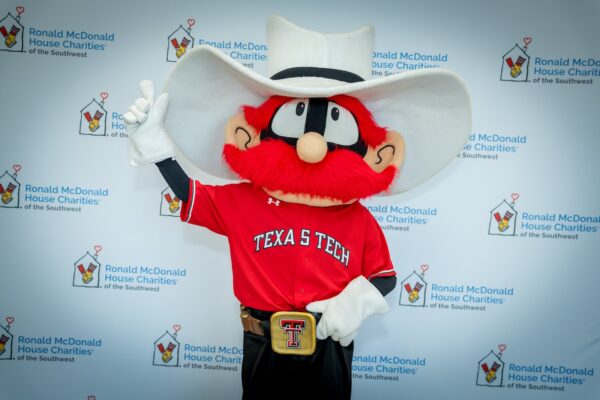 Raider Red poses in front of a Ronald McDonald House Southwest banner at the Quarterback S.A.C.K. Kick-Off Lunch