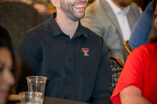 A guest in a Texas Tech polo laughs with others at the Kick-Off Lunch