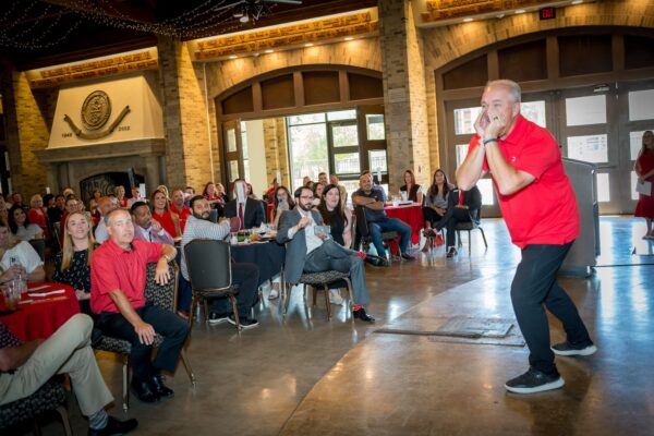 A speaker gestures to a laughing audience at the Kick-Off Lunch